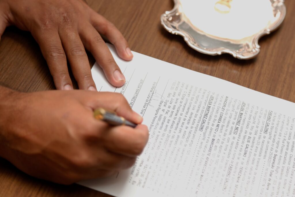 pexels photo 11296102 11296102 Hand signing a contract on a wooden desk, emphasizing business formalities.