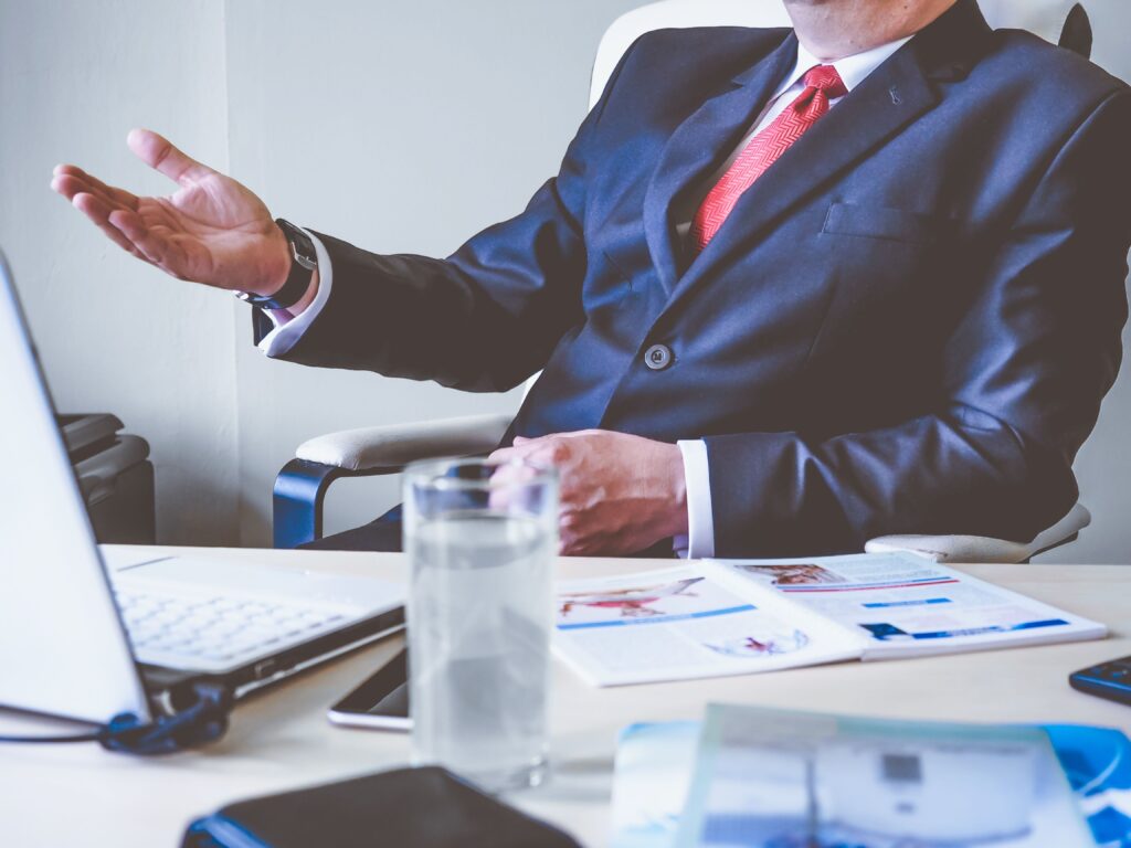 pexels photo 288477 288477 Professional man gesturing in a business meeting at an office desk, conveying confidence and leadership.