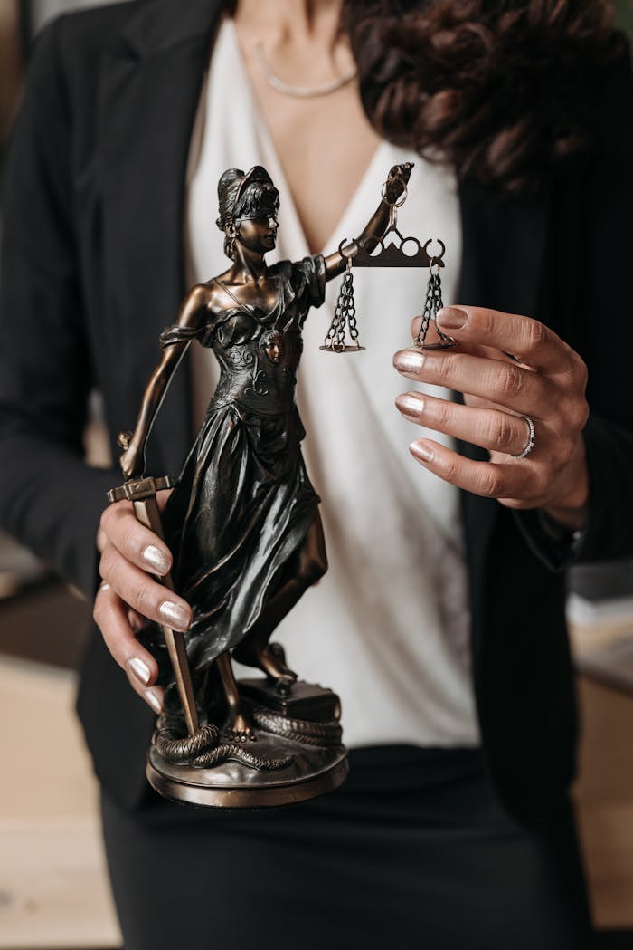 services-02 Close-up of Lady Justice statuette held by a lawyer, symbolizing law and justice.